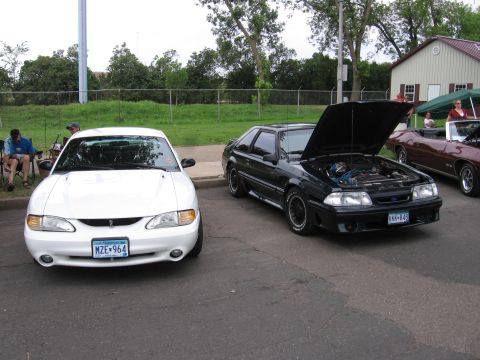 1989 Ford Mustang - A black 1989 Ford Mustang is parked with its hood open, next to a white car.