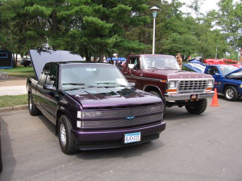 1989 Ford Mustang - Two pickup trucks are parked side-by-side at an outdoor event.