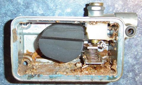 1972 Chevrolet C/K Pickup - Carburetor float bowl interior shows significant buildup of debris around the float and spring mechanism.