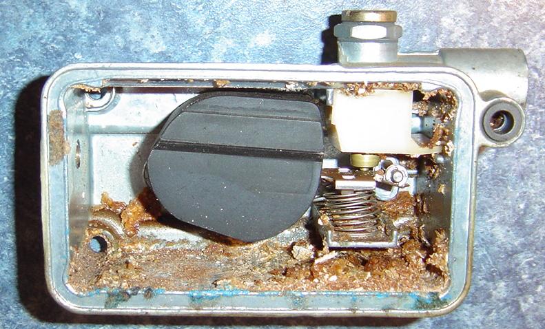 Carburetor float bowl with debris and a black float