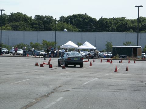 2001 Mercury Grand Marquis - A BMW E36 sedan navigates an autocross course marked by orange cones in a parking lot.