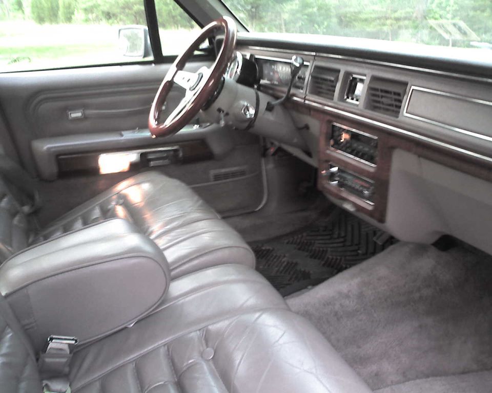 Gray car interior with wood-rimmed steering wheel and woodgrain dash trim