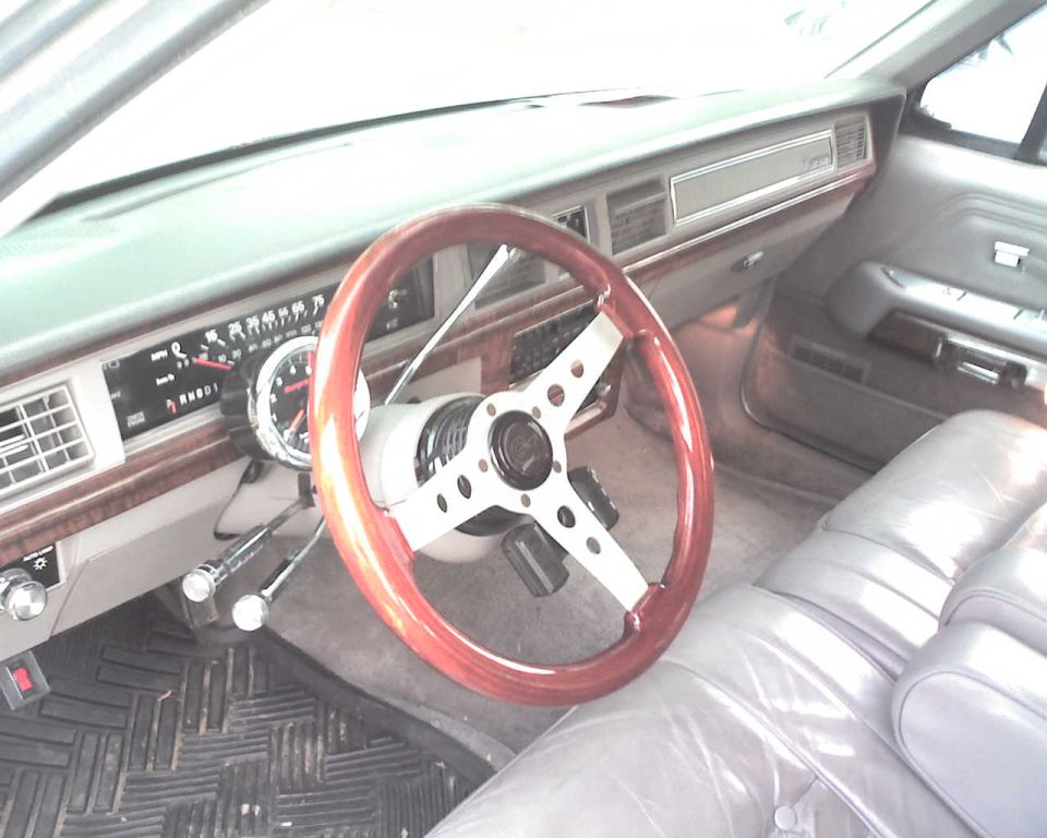 Car interior with aftermarket wood steering wheel and gray leather seats