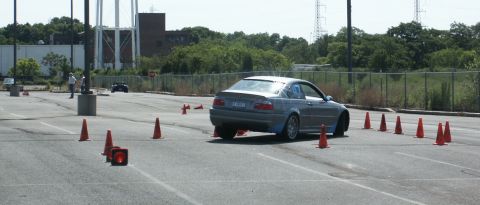 2001 Mercury Grand Marquis - A gray BMW 3 Series sedan maneuvers through an autocross course marked by orange cones.