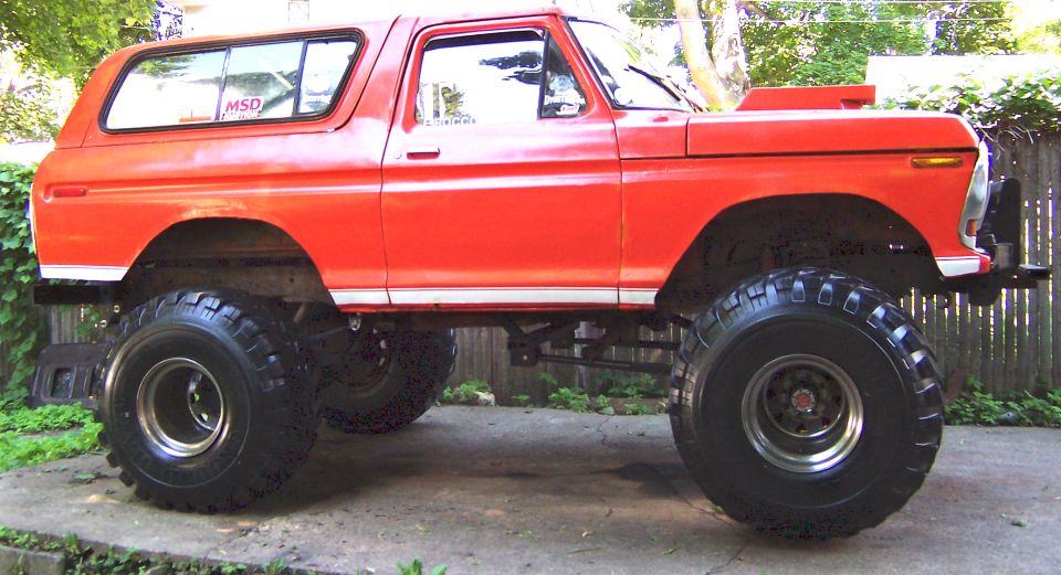 Red 1978 Ford Bronco lifted with large tires and scoop on hood