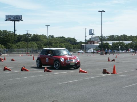 2001 Mercury Grand Marquis - A red Mini Cooper navigates an autocross course marked by orange cones on a sunny day.