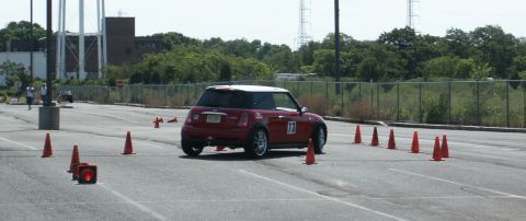 2001 Mercury Grand Marquis - A red Mini Cooper with a white roof navigates a cone-filled autocross course on a sunny day.