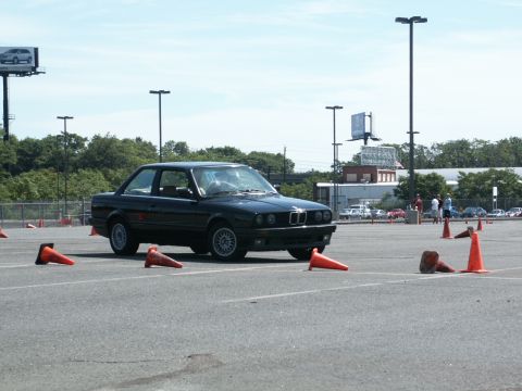 2001 Mercury Grand Marquis - A black BMW E30 coupe navigates a course marked by orange cones on a sunny day.