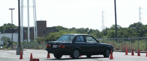 2001 Mercury Grand Marquis - A black BMW E30 coupe is seen at an autocross event with orange cones marking the course.