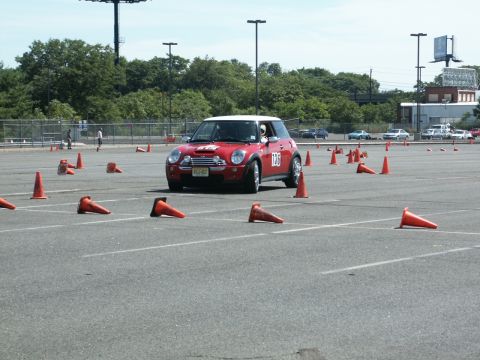 2001 Mercury Grand Marquis - A red Mini Cooper drives through an autocross course marked by orange traffic cones on a paved lot.