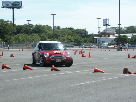 2001 Mercury Grand Marquis - A red Mini Cooper navigates an autocross course marked by orange cones on a sunny day.
