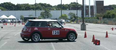 2001 Mercury Grand Marquis - A red Mini Cooper with a white roof navigates an autocross course marked by orange cones.