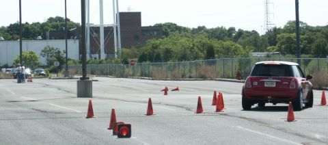2001 Mercury Grand Marquis - A red Mini Cooper is seen from the rear, driving through an obstacle course of orange traffic cones.