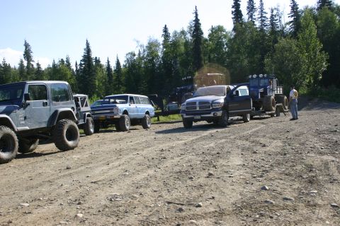 2003 Jeep TJ - A gray 2003 Jeep TJ is parked on a dirt road alongside other vehicles and a tractor.
