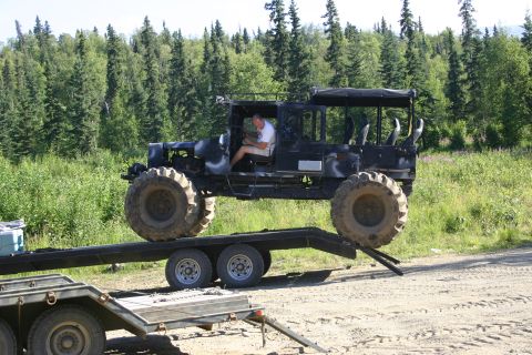2003 Jeep TJ - A modified black off-road vehicle with oversized tires is being loaded onto a trailer.