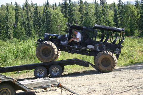 2003 Jeep TJ - Custom off-road vehicle with oversized tires on a trailer in a wooded area.