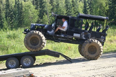 2003 Jeep TJ - A driver maneuvers a heavily modified vehicle with oversized tires onto a flatbed trailer.