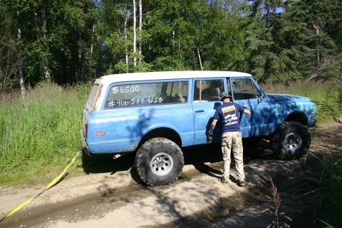 2003 Jeep TJ - Blue lifted station wagon with off-road tires, price and phone number on rear window.