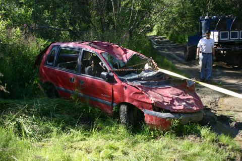 2003 Jeep TJ - A severely damaged red minivan is partially submerged in mud and grass, with a tractor in the background.