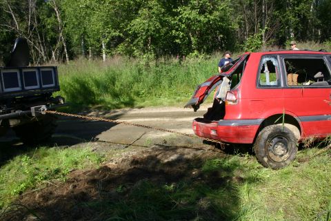 2003 Jeep TJ - A red SUV with its rear hatch open and broken window is being towed by another vehicle.