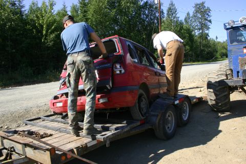 2003 Jeep TJ - Red hatchback being loaded onto a trailer by two men, with a tractor nearby.