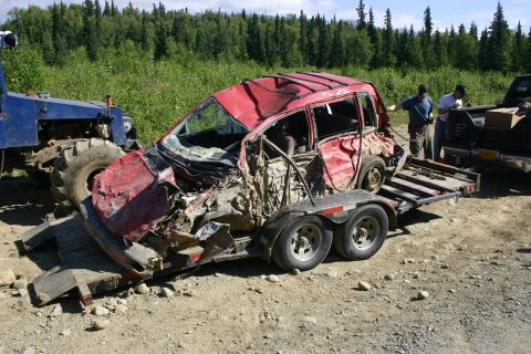 2003 Jeep TJ - A severely damaged red SUV is being loaded onto a trailer, with a tractor and pickup truck assisting.
