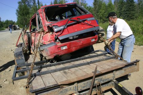2003 Jeep TJ - A heavily damaged red car, identified by 'Eagle' and 'Summitt' badging, is being loaded onto a trailer by two people.