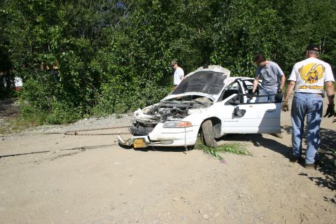 2003 Jeep TJ - A white sedan with its hood up and front end damaged is being towed by a chain.