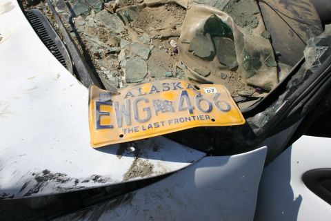 2003 Jeep TJ - Vehicle wreckage includes a bent Alaska license plate and broken glass.