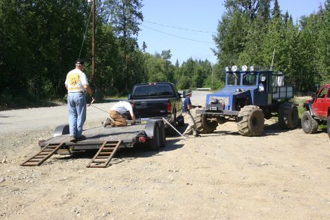 2003 Jeep TJ - A blue custom off-road vehicle is parked next to a black pickup truck and a red Jeep.
