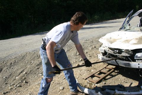 2003 Jeep TJ - Man attempts to work on a wrecked vehicle on a dirt road.