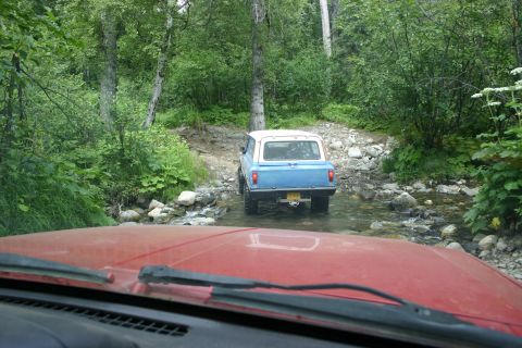 2003 Jeep TJ - Two vehicles navigating a rocky stream bed in a wooded area.