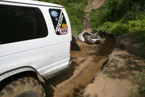 2003 Jeep TJ - Off-road scene shows a white van next to a ditch where another vehicle has overturned.