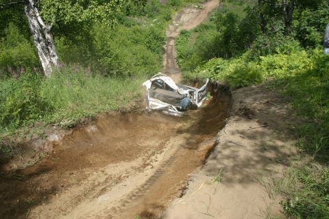2003 Jeep TJ - A vehicle is stuck in a ditch on a dirt path surrounded by trees and vegetation.