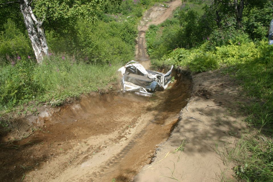 White vehicle stuck in a dirt ditch on an off-road trail