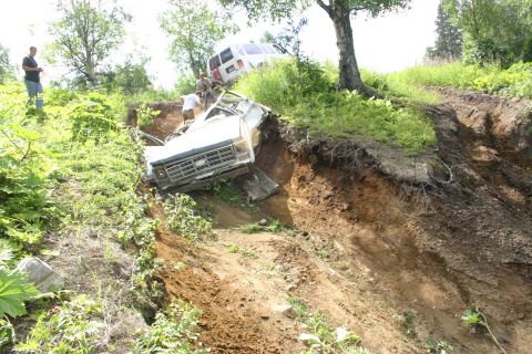 2003 Jeep TJ - Two vehicles are stuck in a deep ditch on a grassy slope.