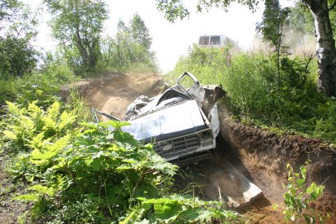 2003 Jeep TJ - A pickup truck is stuck in a ditch, with a van visible on the hill behind it.