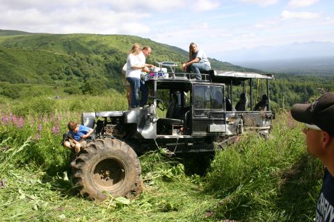 2003 Jeep TJ - People gathered on a custom off-road vehicle in a scenic, grassy landscape.
