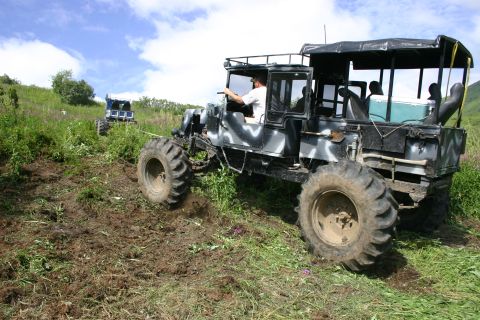 2003 Jeep TJ - Two custom off-road vehicles navigate a challenging muddy and grassy terrain.