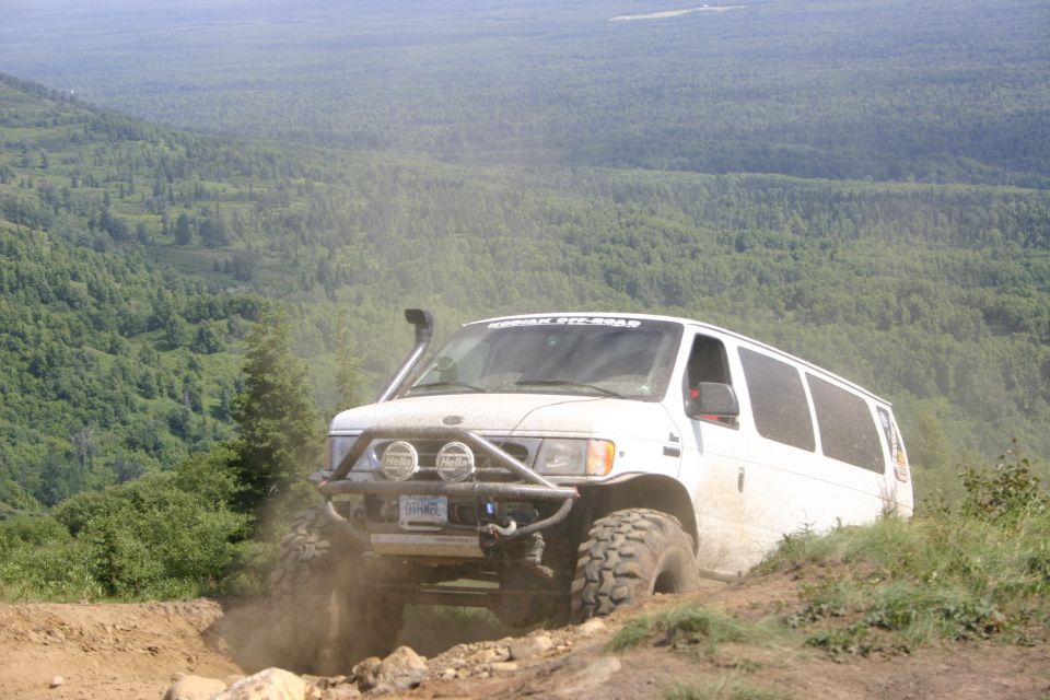 White van with snorkel and off-road tires climbing a dirt hill. Text on windshield reads 'MERIDIAN 4X4 ROAD'