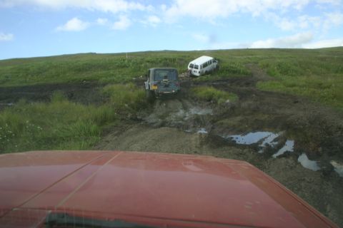 2003 Jeep TJ - Two vehicles attempt to traverse a challenging muddy terrain under a cloudy sky.