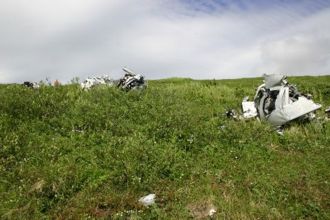 2003 Jeep TJ - The remnants of a crash are visible in a field of green grass and wildflowers.