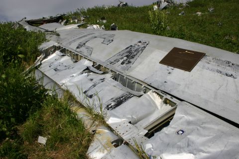 2003 Jeep TJ - Wreckage of an aircraft lies scattered in a grassy field, with a memorial plaque attached to a large piece of debris.
