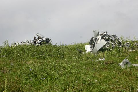 2003 Jeep TJ - Debris from a plane crash is visible on a grassy slope, with two individuals observing the wreckage.