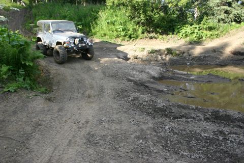 2003 Jeep TJ - A silver Jeep TJ navigates a rough, muddy off-road trail.