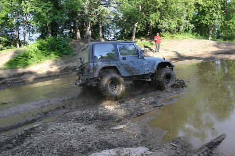 2003 Jeep TJ - Jeep TJ tackling off-road terrain with mud and water obstacles.