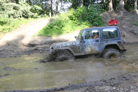 2003 Jeep TJ - Jeep TJ Wrangler navigating a muddy trail, with a person watching from a hill.