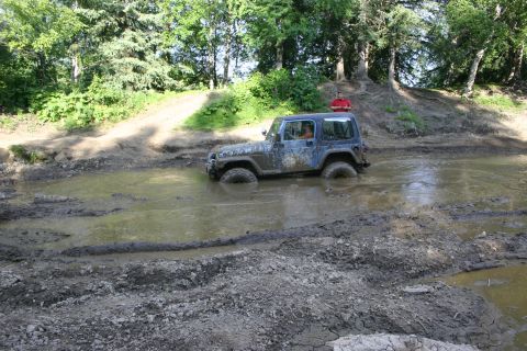 2003 Jeep TJ - A Jeep TJ navigates a deep mud pit on an off-road trail.
