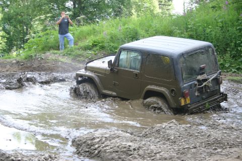 2003 Jeep TJ - Jeep TJ navigating a challenging muddy terrain, with a bystander documenting the event.
