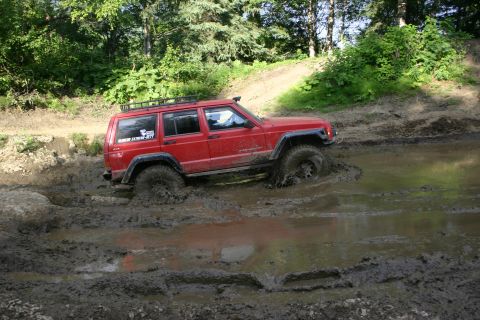 2003 Jeep TJ - Jeep Cherokee XJ navigating a challenging muddy terrain, tires deep in the mire.